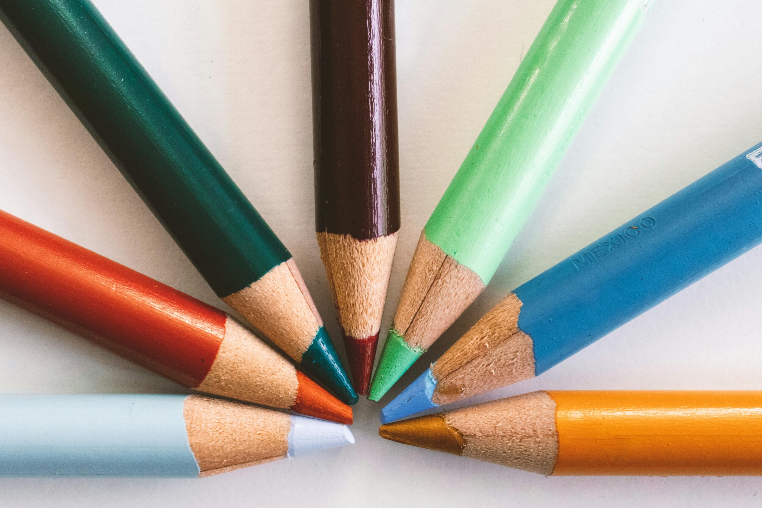 Close-up of colorful pencils arranged in a circle on a white background, highlighting creativity and art.